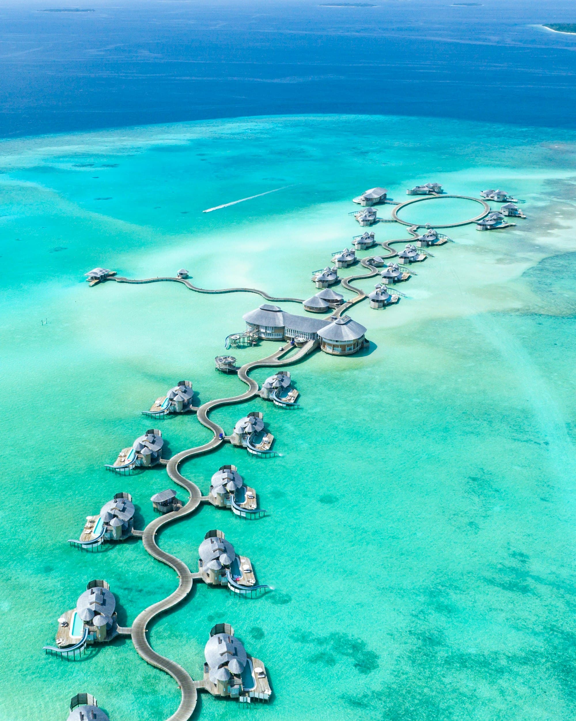 Aerial view of overwater villas winding across a turquoise Maldives lagoon